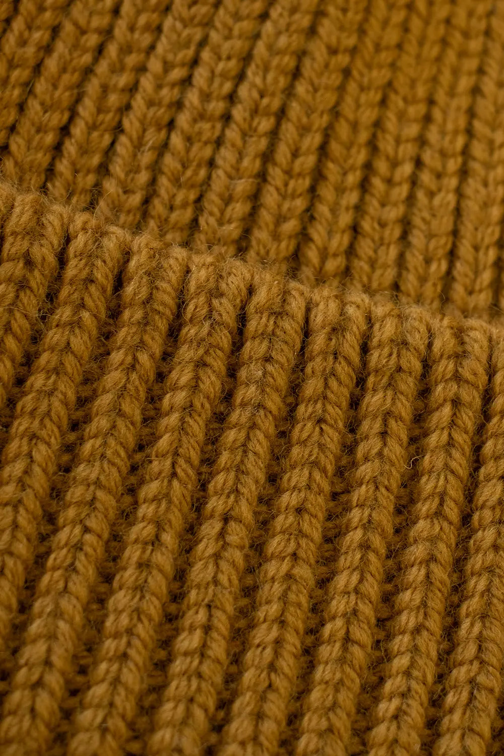 Close-up of a mustard yellow ribbed knit fabric texture, showing the detailed vertical rows of yarn.
