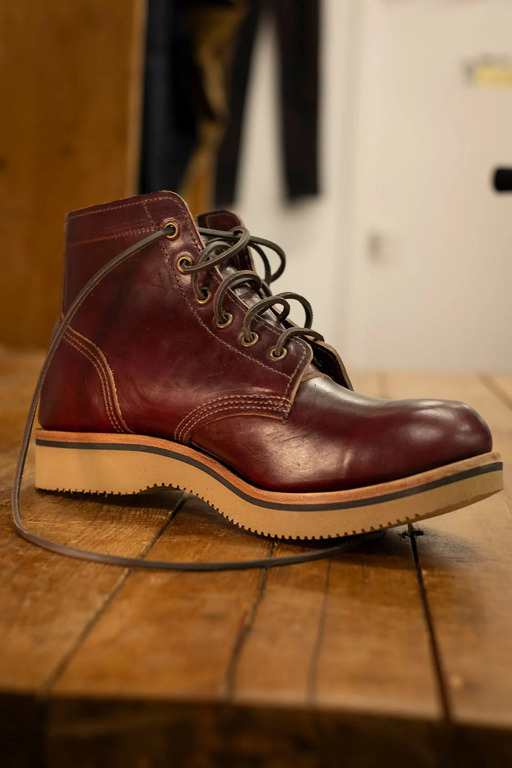 A Ankle biter boot, resting on a rustic wooden surface with a blurred indoor background.