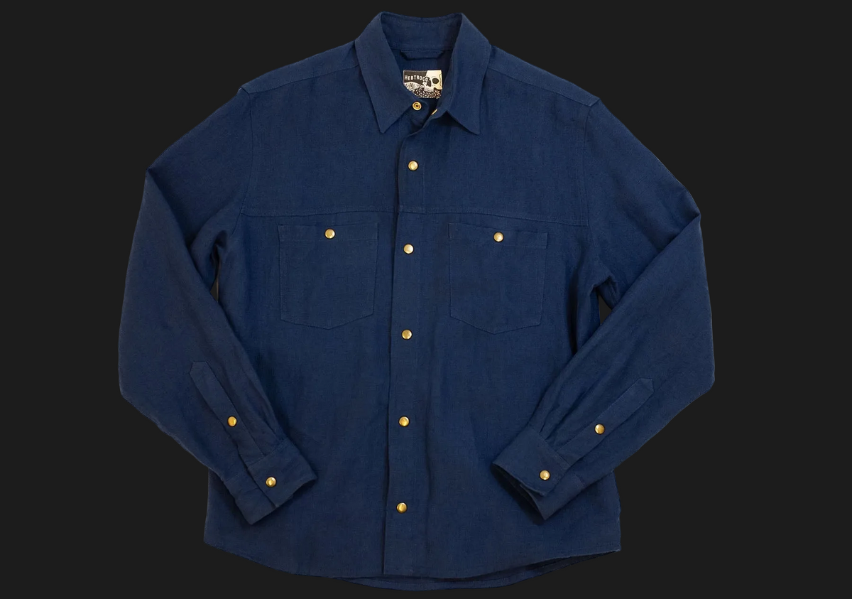 A dark blue long-sleeve button-up shirt with gold buttons, laid flat against a dark background.