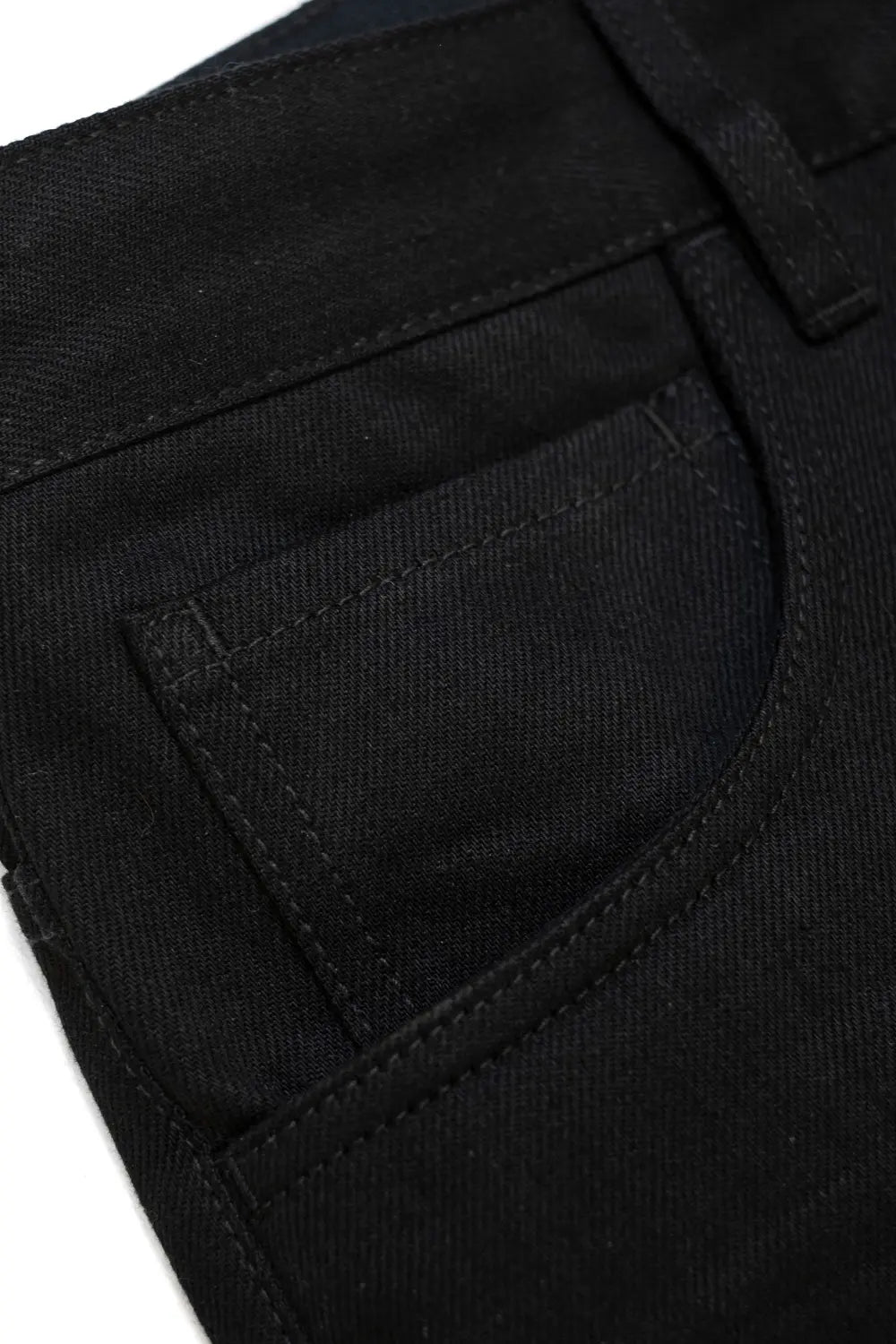 Close-up detail of a black denim pair showing the back pocket and waistband stitching.