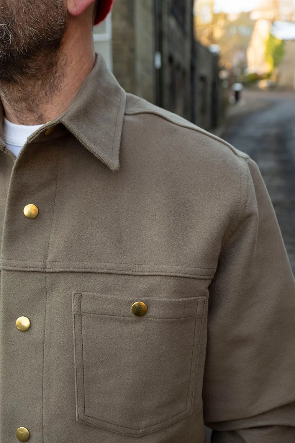 A close-up of Ed wearing a Lovat Ironshirt  with brass buttons, set against a blurred outdoor street background.