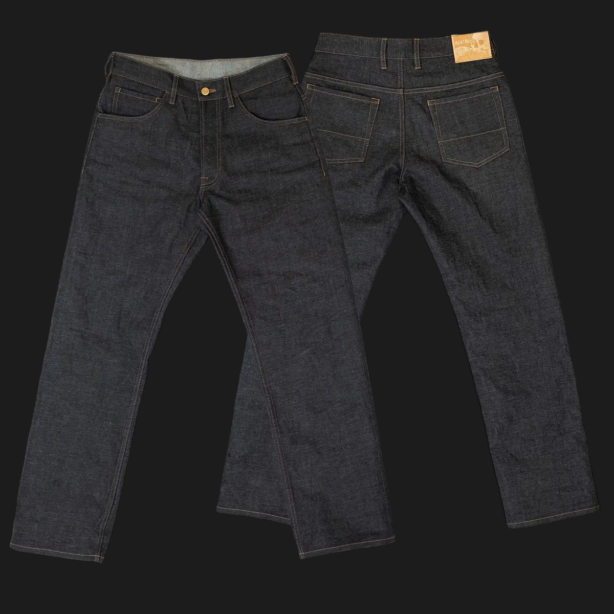 Two views of dark indigo denim jeans laid flat on a black background, showing the front and back details including the pockets, belt loops, and a tan leather brand patch on the back waistband.